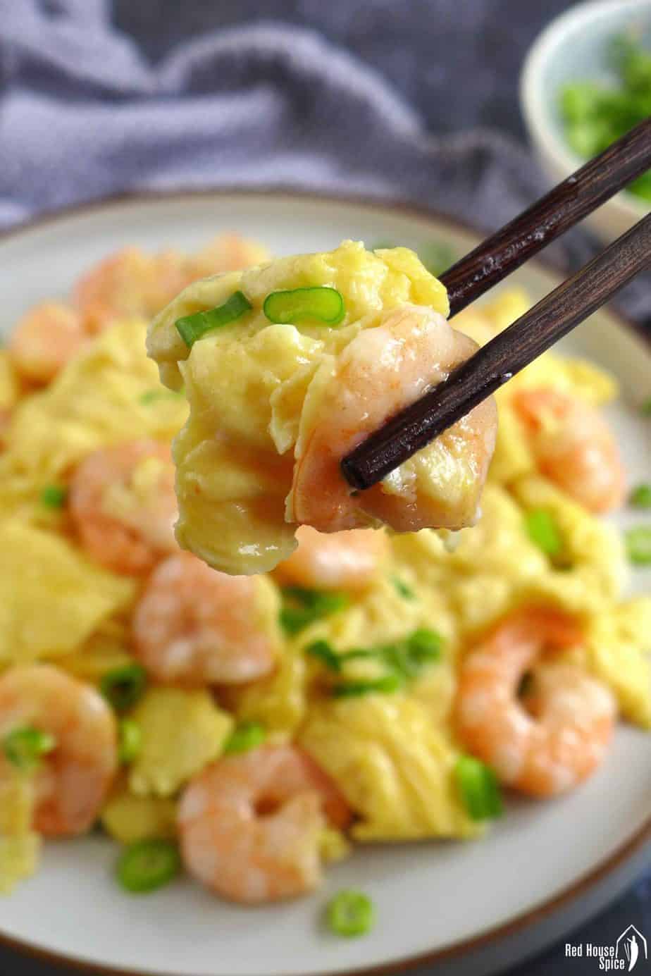 Chopsticks picking up a piece of scrambled egg and shrimp