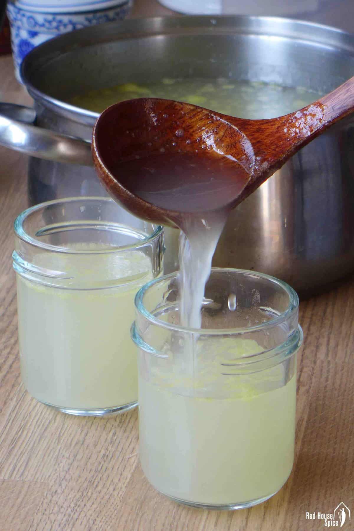 pouring chicken stock into a jar.