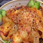 slices of pork over cucumber with a spicy dressing with overlay text that says Sichuan pork slices.