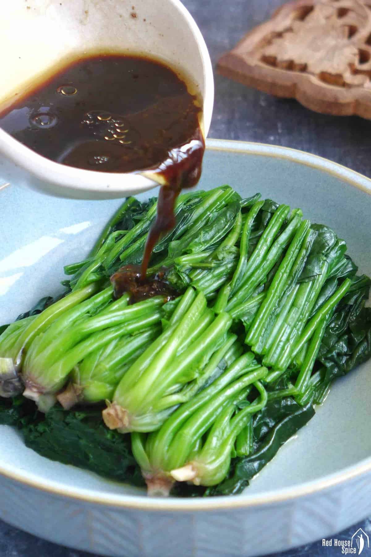pouring sauce over blanched spinach.
